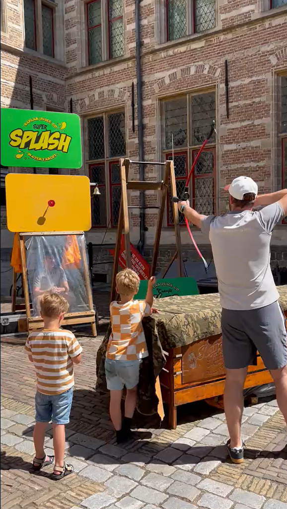 Vader schiet met pijl en boog terwijl kinderen toekijken